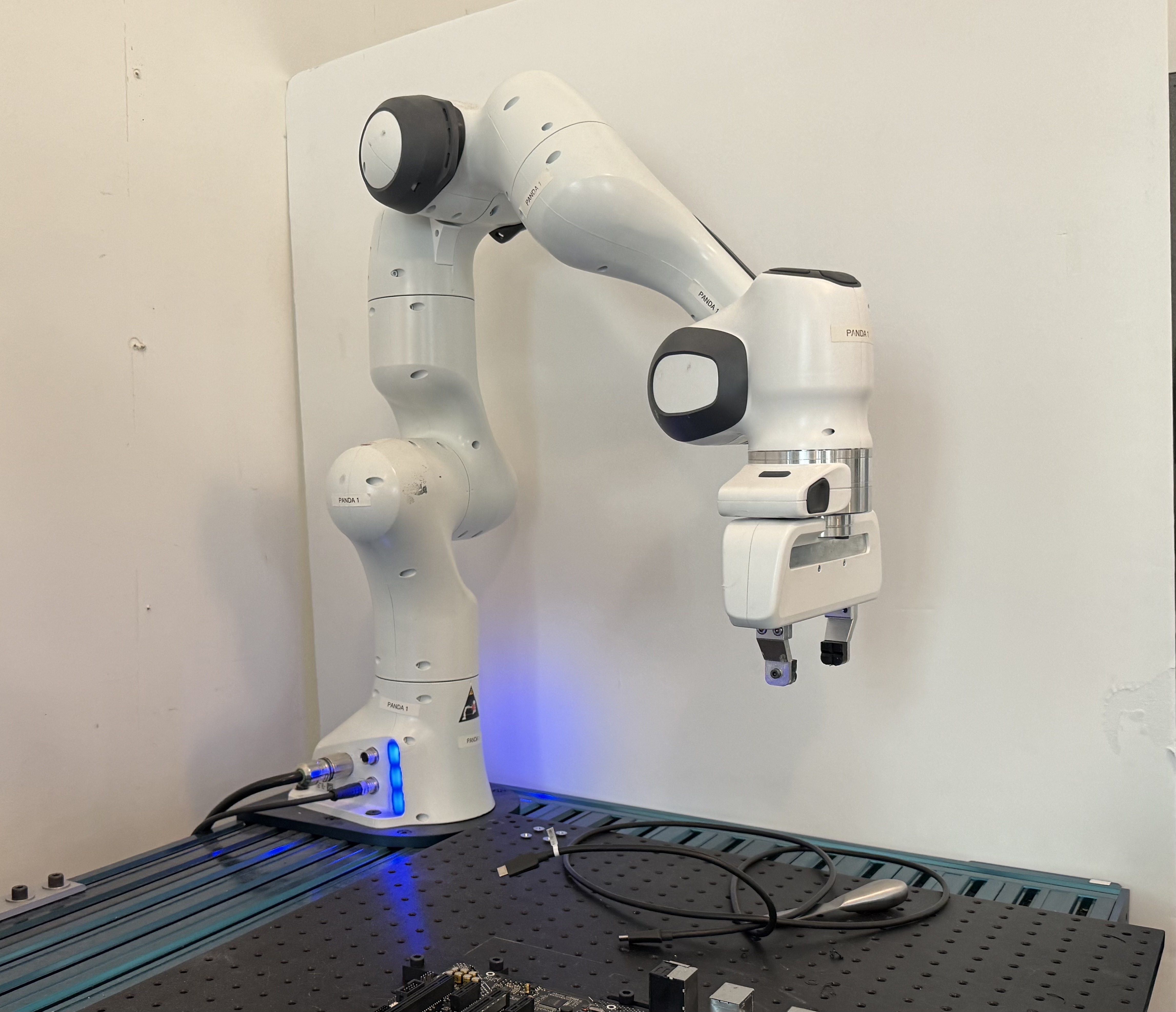 Franka Panda arm installed over the optical-table workspace at MIT